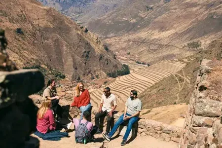 a group of people sitting on a stone ledge in a valley