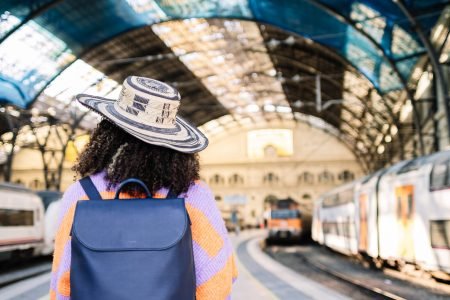 a woman with a backpack and hat standing in a train station