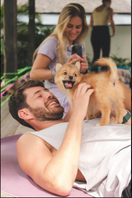 A happy man playing with small during a Puppy Yoga Wellbeing Experience in Canggu, Bali.