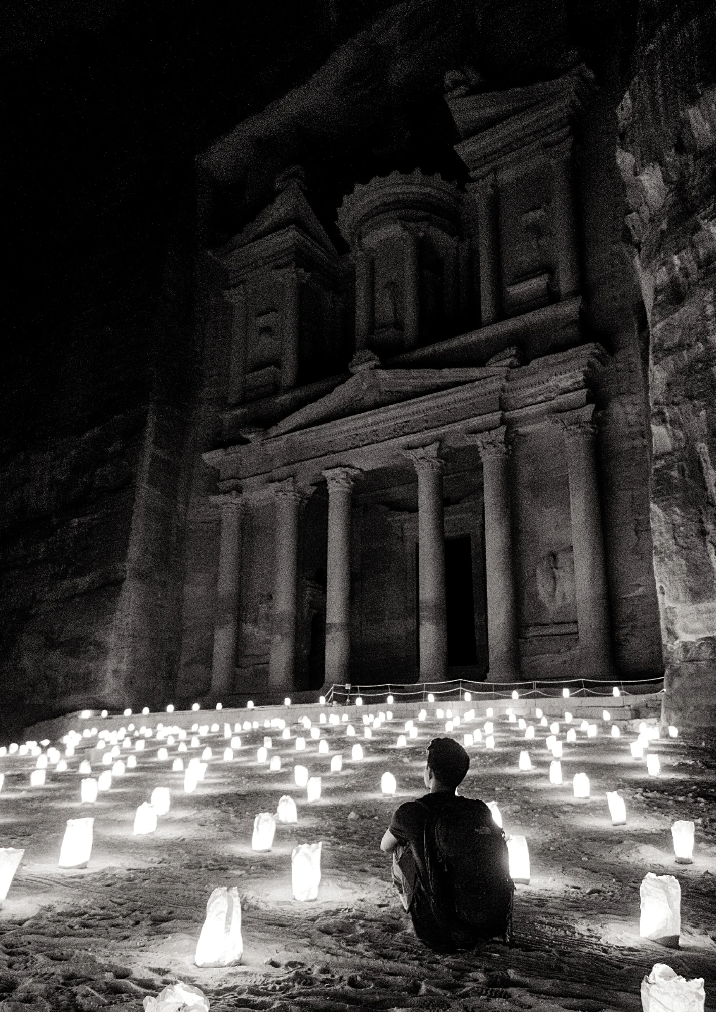 A man sitting in meditation by a church, holy sacred site surrounded by lit candles | Exped Owl