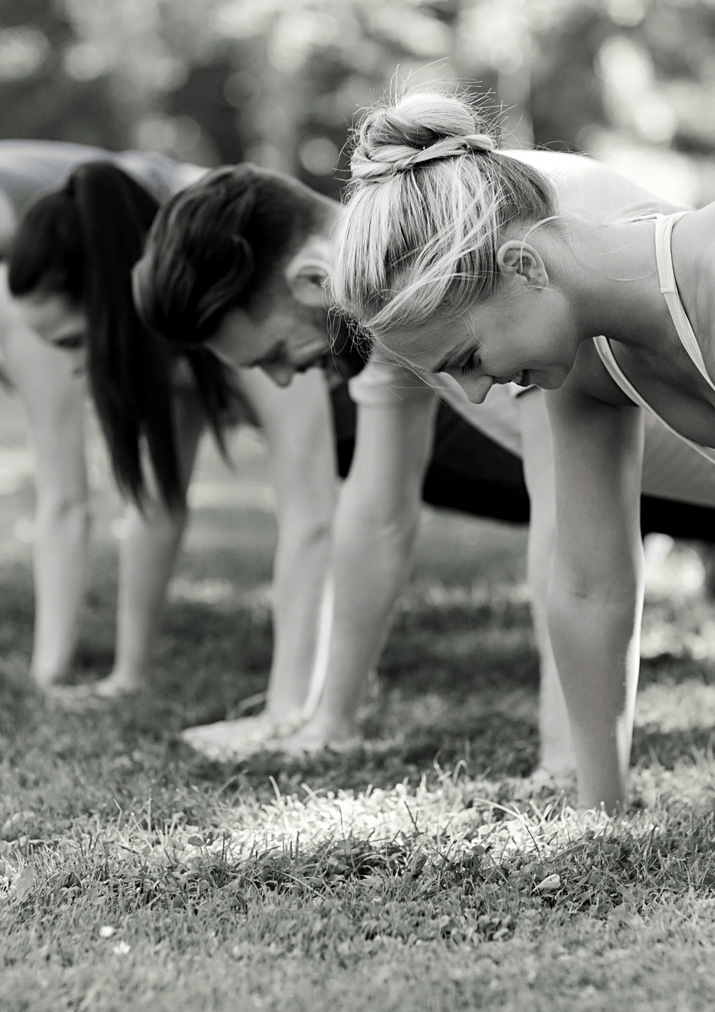 Smiling people in fitness class, doing push-ups/ planks. Bootcamp group. Exped Owl